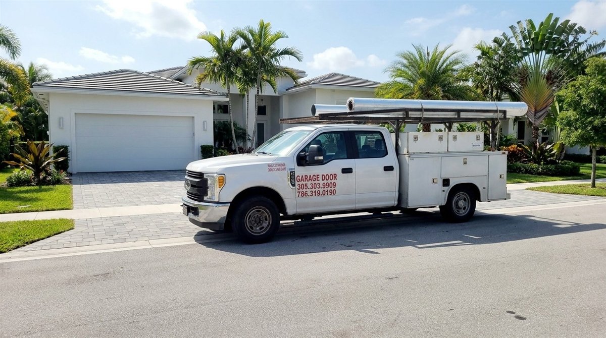 All Tech service truck with rolled garage doors on its rack, parked in front of a Miami home